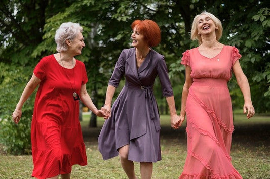 A trio of older women holding hands and almost skipping together. Much joy and happiness.