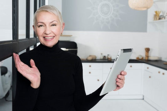 Mid aged woman sitting in her kitchen, notebook in hand. She is smiling because she realised she can flip any money blocks that are running her life.